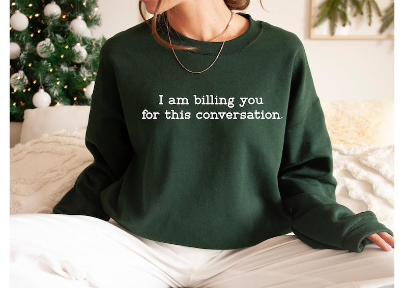 May include: A dark green sweatshirt with the text "I am billing you for this conversation." printed in white.