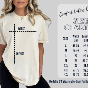 May include: Cream-coloured t-shirt with a size chart. The chart lists sizes S to 4XL, with width and length measurements in inches. The text "Comfort Colors C1717" is at the top. The model is 5'2" and wearing a medium.