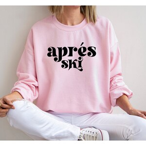 May include: A pink sweatshirt with the text "apr&egrave;s ski" in black retro-style lettering.
