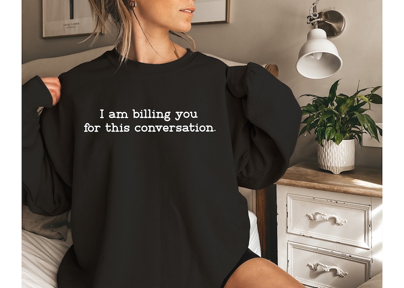 May include: A black sweatshirt with the text "I am billing you for this conversation." printed in white.