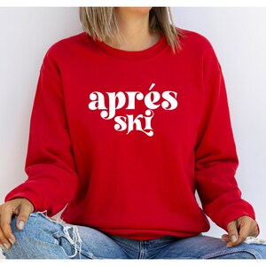 May include: A red sweatshirt with the text "apr&egrave;s ski" in white retro-style lettering.