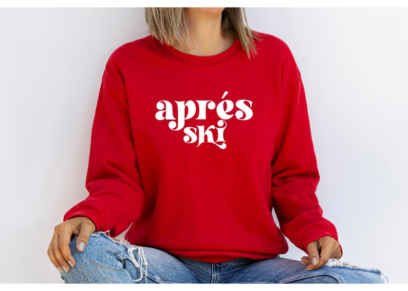 May include: A red sweatshirt with the text "apr&egrave;s ski" in white retro-style lettering.