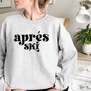 May include: A gray sweatshirt with the text "apr&egrave;s ski" in black, stylized lettering.