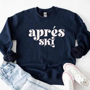 May include: A navy blue sweatshirt with the text "apr&egrave;s ski" in white retro-style lettering.