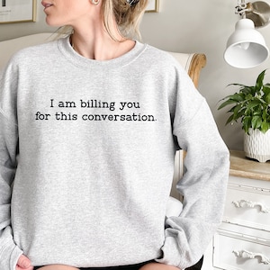 May include: A gray sweatshirt with the text "I am billing you for this conversation." printed on the front.