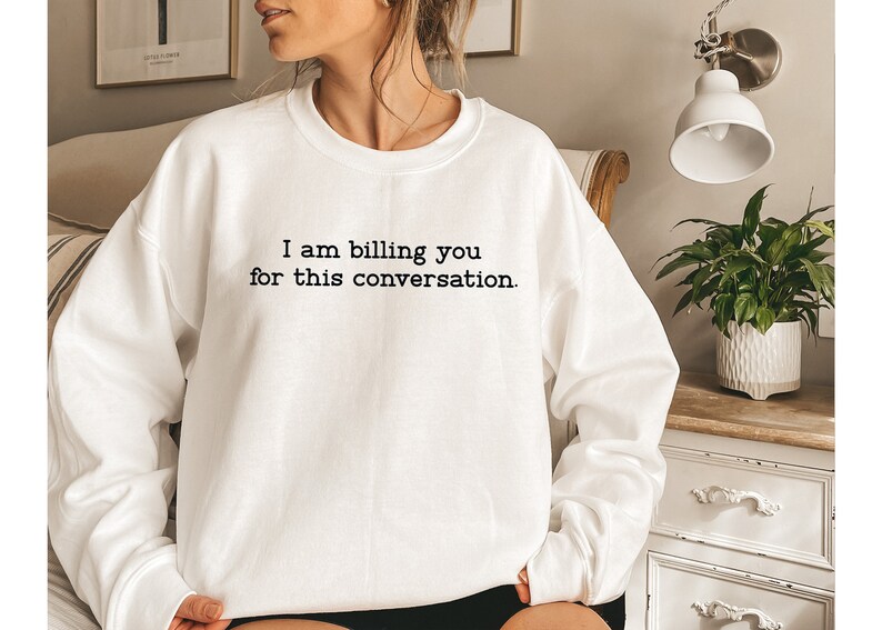 May include: White sweatshirt with the text "I am billing you for this conversation." printed in black.