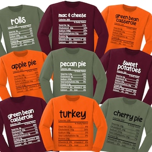 May include: Nine orange, green, and maroon long-sleeved shirts with Thanksgiving-themed food names and nutrition facts printed on the front. The shirts feature the following foods: rolls, mac & cheese, green bean casserole, apple pie, pecan pie, sweet potatoes, green bean casserole, turkey, and cherry pie.