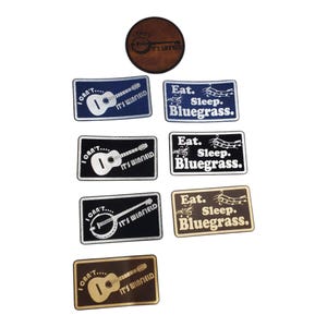 May include: A collection of patches with musical instrument designs and text. The patches feature a guitar, banjo, and musical notes. Text includes "I can't... It's Winfield" and "Eat. Sleep. Bluegrass."
