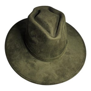 Puede incluir: Sombrero fedora verde oliva con ala ancha. El sombrero tiene una copa estructurada y una textura suave similar al ante. El ala del sombrero mide aproximadamente 7,6 cm de ancho.