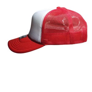 May include: A red and white trucker hat with a mesh back. The hat has a red brim and a white front panel. The mesh back is red. The hat is a classic style.
