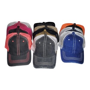 May include: A collection of trucker hats in various colors, including black, blue, orange, and pink. Each hat features a mesh back and a distressed, vintage look. The hats have a curved brim and adjustable closure.