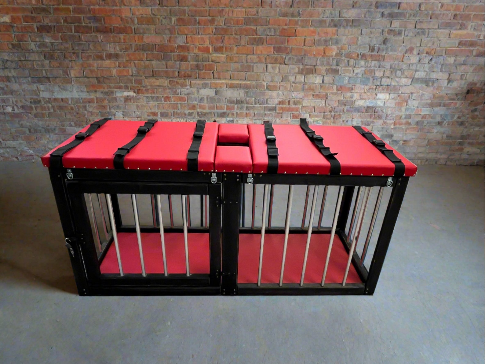 Red padded bdsm massage table with built-in metal cage and restraint straps, designed for bondage play in a sex dungeon.