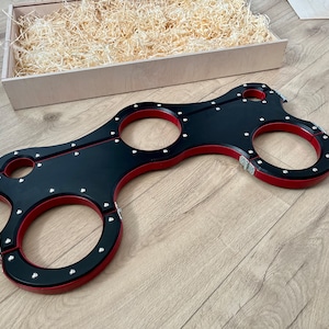 Peut inclure: Contrainte en bois noir et rouge avec plusieurs anneaux. Les contraintes sont en bois et ont une finition noire avec des accents rouges. Les anneaux sont en métal et sont fixés au bois à l'aide de vis.