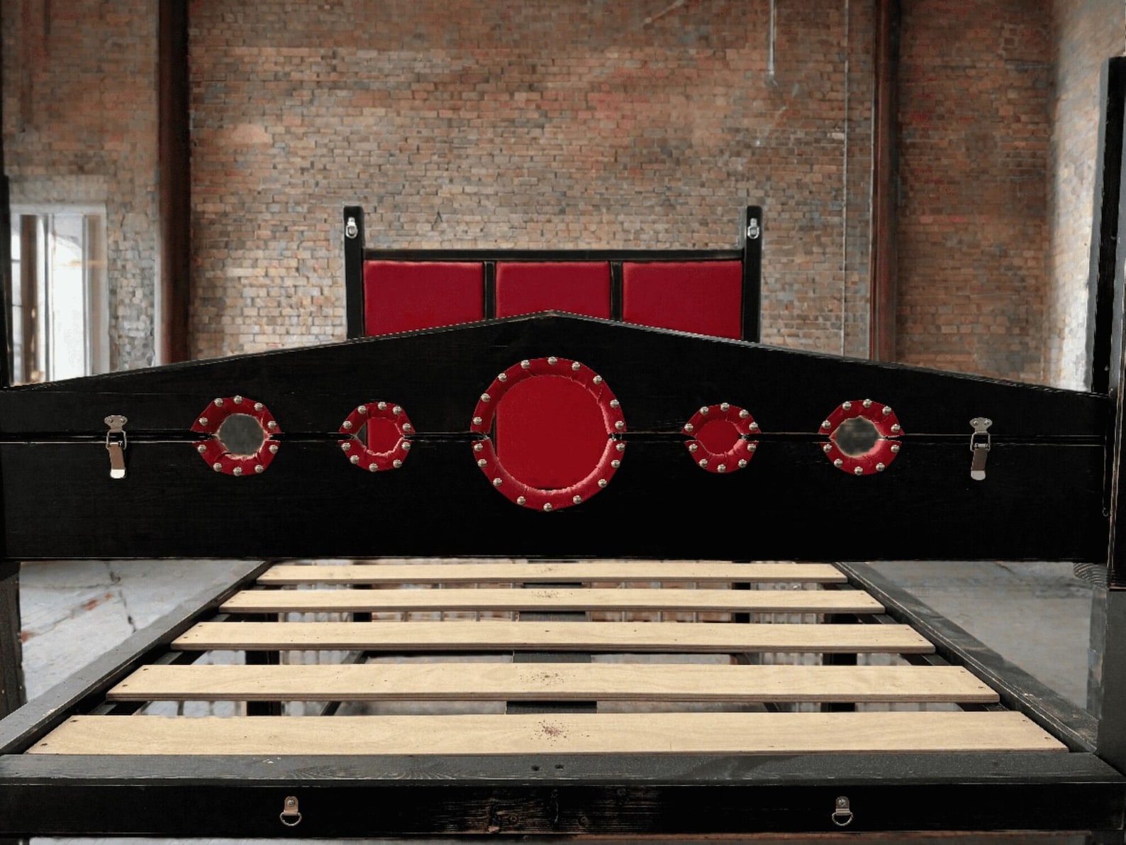 Front view of king size bdsm bed with red padded stockade panel, designed for bondage restraint in a sex dungeon setting.