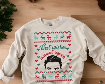 May include: A cream-colored sweatshirt with a festive Christmas design. The design features a man's face, reindeer, hearts, and the text "Best wishes warmest regards".