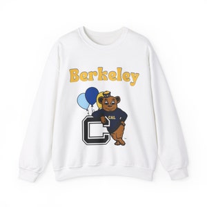 May include: White sweatshirt with a yellow "Berkeley" graphic, a cartoon bear wearing a blue and white sailor hat, and a blue and white balloon.