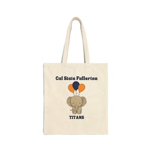 Könnte beinhalten: Eine beige Tragetasche mit einem dunkelblauen und orangefarbenen Elefantenmotiv und dem Text "Cal State Fullerton Titans".