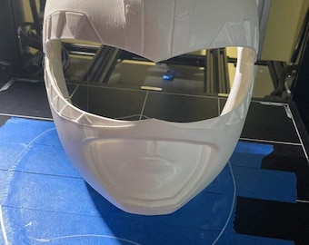 May include: White plastic 3D printed helmet with a detailed design. The helmet has a visor and a pointed top.