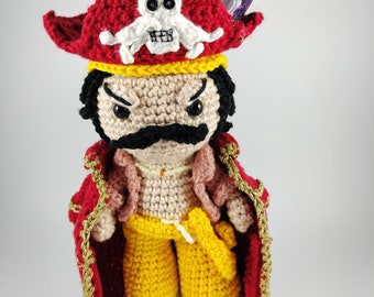 May include: A crocheted pirate doll with a red hat, a skull and crossbones design, a red coat with gold trim, yellow pants, and brown shoes.