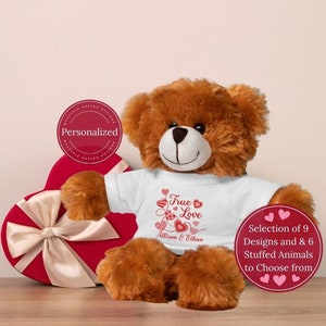 May include: A brown teddy bear wearing a white t-shirt with the text "True Love" and two hearts. The shirt also has the names "Allison & Ethan" printed on it. The bear is sitting in front of a red heart-shaped box with a white ribbon. The image also includes a red circle with the text "Selection of 9 Designs and 6 Stuffed Animals to Choose from".