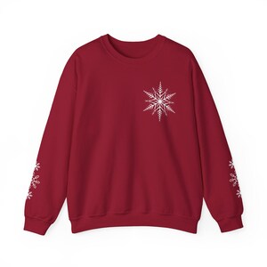 May include: A red sweatshirt with a white snowflake design on the front and smaller snowflakes on the sleeves.