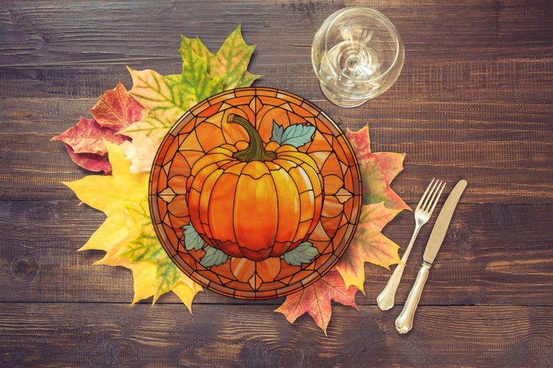 Puede incluir: Un plato de vidrio coloreado con un dise&ntilde;o de calabaza. El plato est&aacute; rodeado de hojas de oto&ntilde;o en tonos de rojo, naranja y amarillo. El plato est&aacute; sobre una mesa de madera.