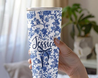 May include: A white and blue floral patterned tumbler with the name "Jessica" in blue script. The tumbler has a silver lid.