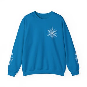 May include: A bright blue sweatshirt with white snowflake designs on the sleeves and a larger snowflake design on the front.
