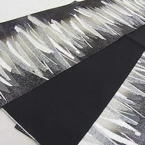 May include: Black fabric with a silver and white abstract pattern. The fabric is folded in half, showing both sides of the pattern.