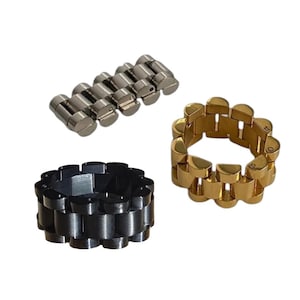 Può includere: Tre anelli e un elemento di cinturino dell'orologio. Un anello è color oro, un altro è nero e il terzo è argentato. L'elemento del cinturino dell'orologio è argentato. Tutti gli articoli hanno un design a maglie.