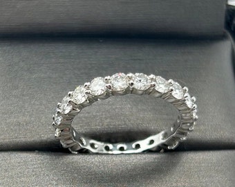 May include: A silver band with a row of round, clear diamonds set in a continuous line.