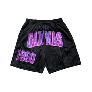 May include: Black athletic shorts with a purple "GAMMAS 1990" graphic printed on the front.