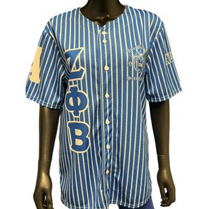 Puede incluir: Una camiseta de b&eacute;isbol a rayas azules y blancas con las letras "Z", "Phi" y "B" en el lado izquierdo. El lado derecho de la camiseta tiene un escudo con el texto "Zeta Phi Beta Sorority, Inc. 1920".