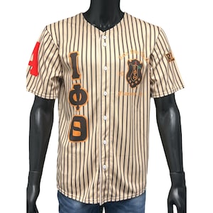 Puede incluir: Una camiseta de b&eacute;isbol a rayas beige y negras con un gran gr&aacute;fico naranja y negro "I &Phi; D" en el lado izquierdo. La camiseta tiene un frente abotonado blanco y un peque&ntilde;o escudo negro y dorado con el texto "Beta Phi Sigma 1919 Founded" en el lado derecho.