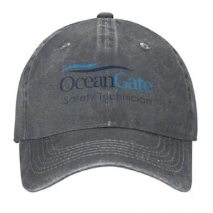 May include: A grey distressed denim baseball cap with the text "OceanGate Safety Technician" and a blue wave logo embroidered on the front.