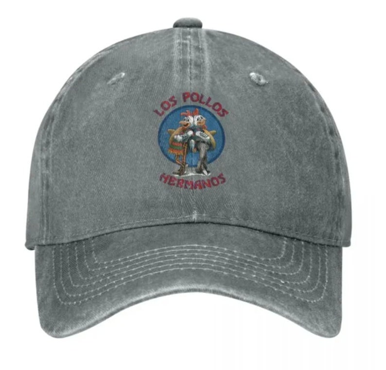May include: A gray distressed denim baseball cap with a vintage-style embroidered logo featuring two chickens and the text "Los Pollos Hermanos".