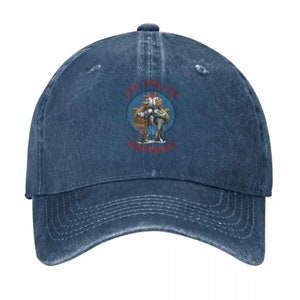 May include: A blue denim baseball cap with a distressed look. The cap features a circular patch with a cartoon image of two birds holding a fish. The text "Los Pollos Hermanos" is printed in red on the patch.