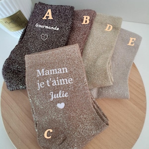 Peut inclure: Un ensemble de cinq chaussettes métallisées scintillantes dans des tons marron foncé, cuivre, bronze, or et argent. La chaussette A porte le texte 'Gourmande' avec un cœur, et la chaussette C porte le texte 'Maman je t'aime Julie' avec un cœur.