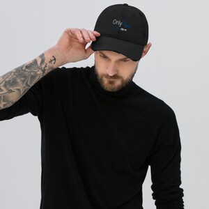 Op de afbeelding: Zwarte distressed baseball cap met de tekst "Only Plans 24/7" geborduurd in wit en blauw. De cap heeft een voorgebogen klep en een versleten, vintage uitstraling.