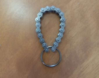 May include: A silver metal keychain with a chain link design and a round ring.