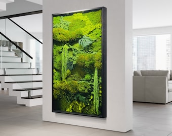 May include: A black framed vertical wall art piece featuring a preserved moss wall. The moss is a variety of green shades and textures. The wall art is hanging on a white wall in a modern home.
