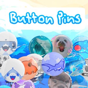 May include: A selection of button pins with diverse designs, featuring cartoon animals, marine life, and the text "Button Pins". The pins display a range of colours, such as blue, white, orange, and purple. The pins are circular and have a glossy finish.