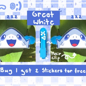 Może przedstawiać: Niebiesko-biała spinka do włos&oacute;w w kształcie rekina z napisem "Great White". Obraz zawiera r&oacute;wnież tekst "Buy 1 get 2 Stickers for free."