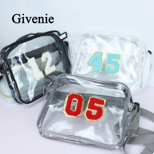 Może przedstawiać: Trzy przezroczyste torby na ramię z tworzywa sztucznego z różnymi kolorowymi numerami z przodu. Torby są czarne, białe i szare. Numery to 12, 45 i 05.