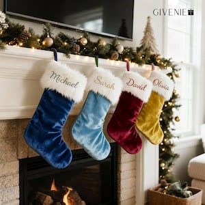 May include: Four velvet Christmas stockings in blue, light blue, burgundy, and gold hang from a fireplace mantel. Each stocking has a white faux fur cuff and a name embroidered in a matching color: Michael, Sarah, David, and Olivia.