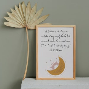 May include: A framed print with a quote by B.F. Skinner about failure. The quote reads, "A failure is not always a mistake, it may simply be the best one can do under the circumstances. The real mistake is to stop trying." The print features a stylized illustration of a crescent moon with a sun and stars in the background.