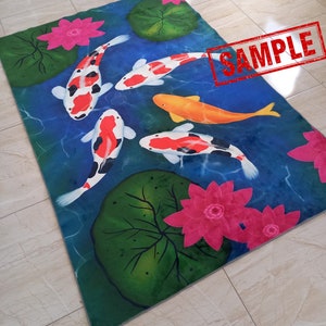 May include: Rectangular rug featuring a pond scene with koi fish, lily pads, and lotus flowers. The koi fish are white, orange, and black, swimming in blue water. Pink lotus flowers and green lily pads are scattered around the pond.