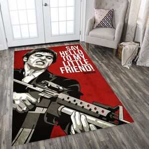 May include: A red and white rug with a black and white illustration of a man holding a gun. The text "Say hello to my little friend! Scarface" is printed on the rug.