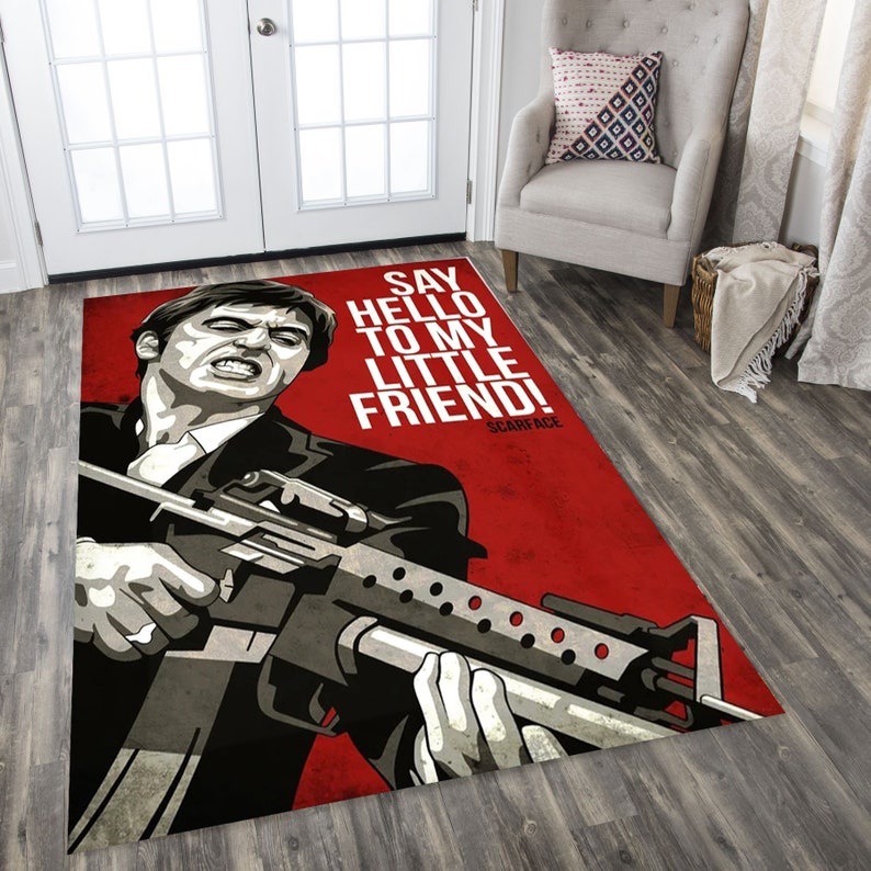 May include: A red and white rug with a black and white illustration of a man holding a gun. The text "Say hello to my little friend! Scarface" is printed on the rug.