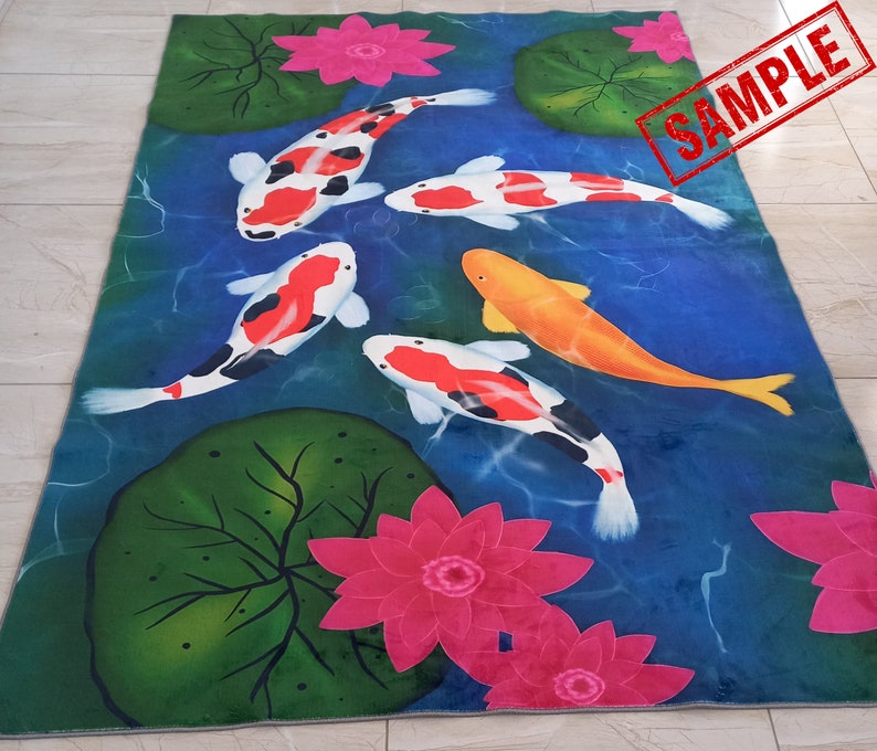 May include: A rectangular rug featuring a pond scene with koi fish and water lilies. The koi fish are white, orange, and black, swimming in blue water. Pink water lilies and green lily pads are also present. The word "SAMPLE" is stamped on the rug.